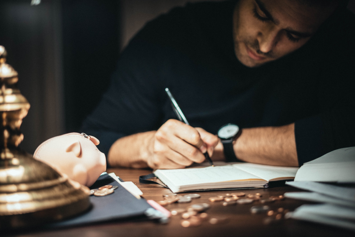 Man counting money and writing in book