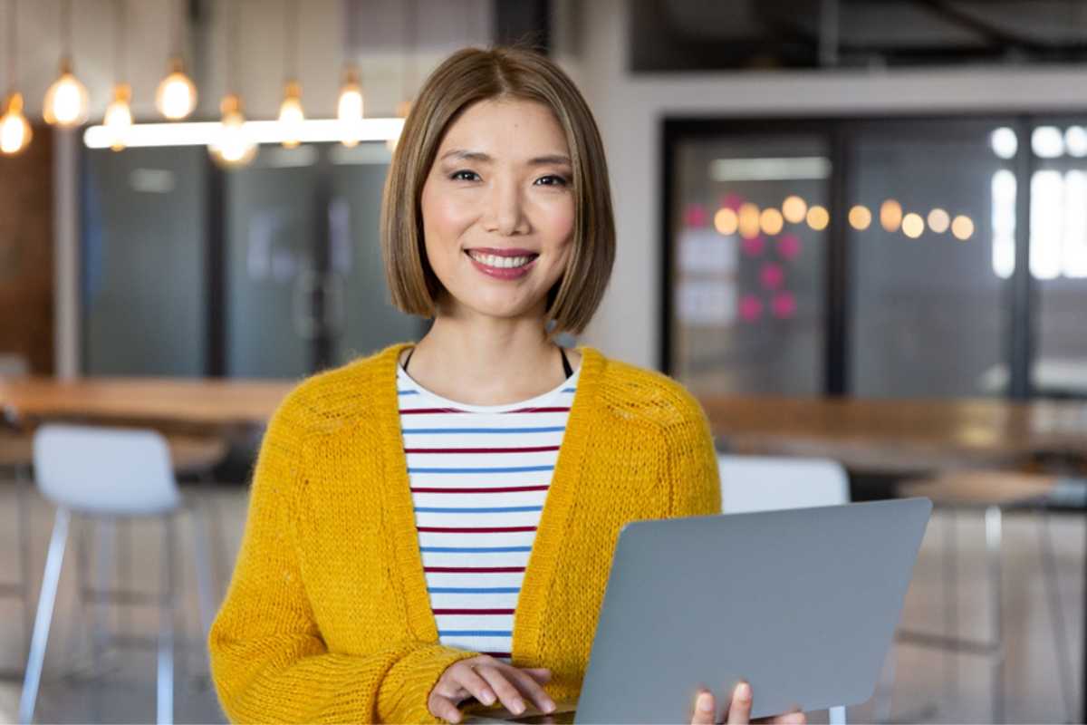 Woman in yellow cardigan holding a laptop